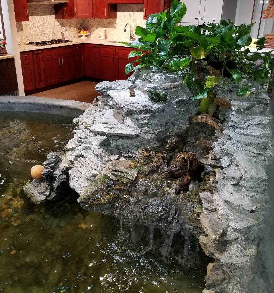 indoor-water-fountain-cascading-waterfall-over-rocks-leading-to-koi-pond